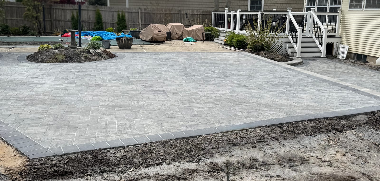 Leveled detail crop of a gray paver patio, showing its original pattern and dark border.
